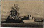 Plate-forme de pierre avec une grande roue au milieu d'un terrain nu, image 1/2